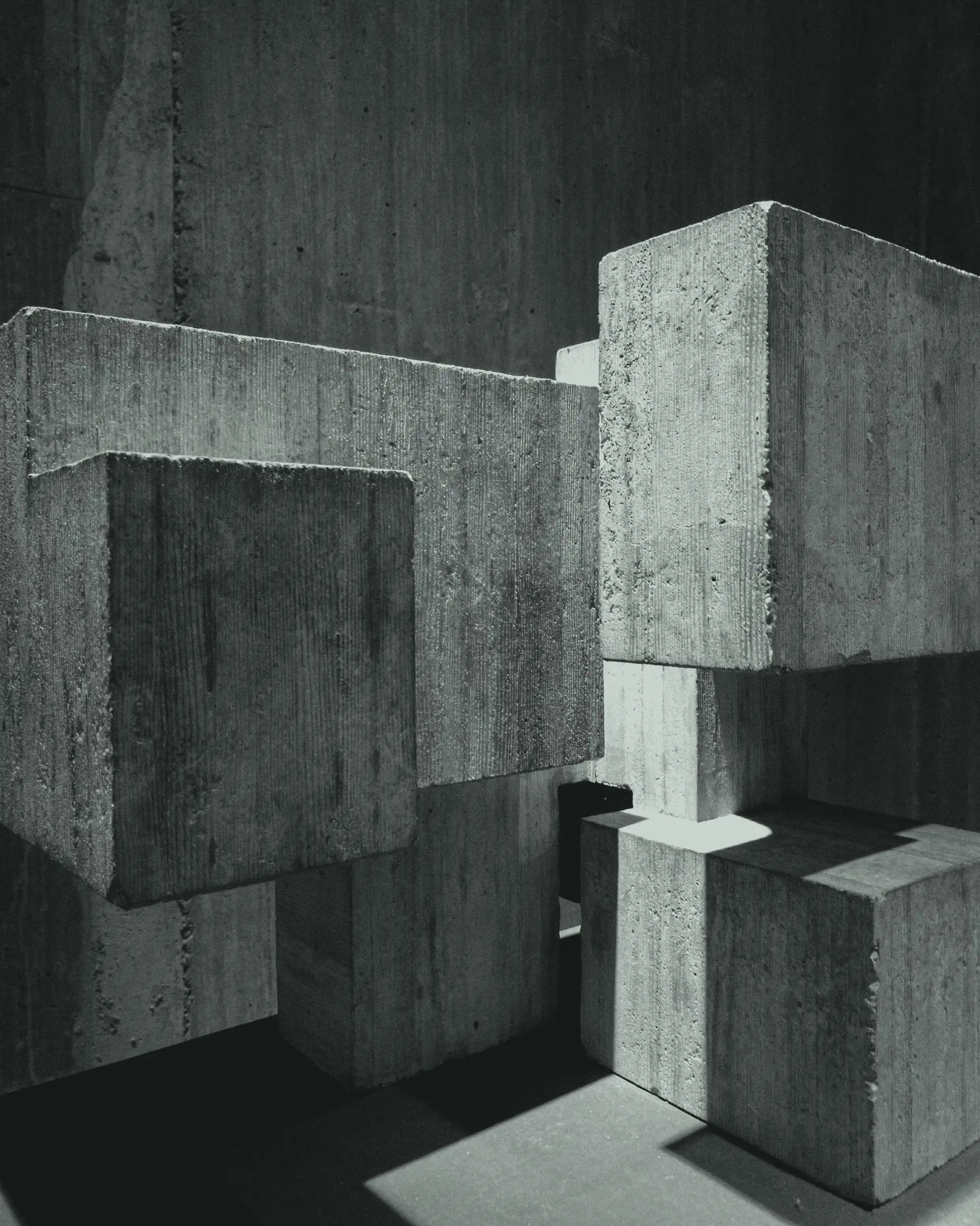 Stacked concrete blocks under raking light, almost sculptural, with very dense blacks.